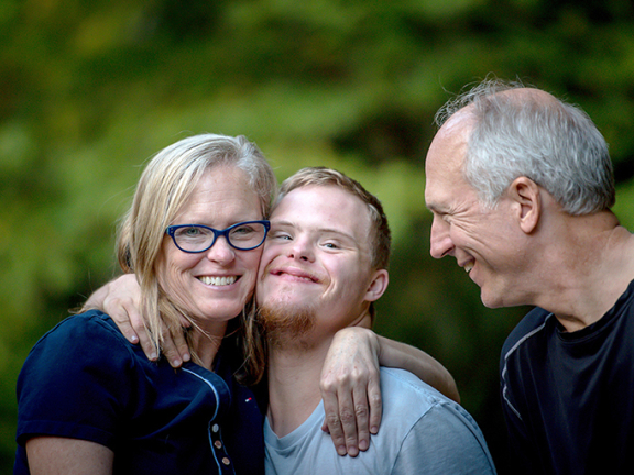 Parents hugging their adult son with down syndrome