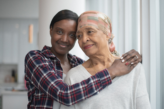 Young adult woman hugging her aging mother and smiling