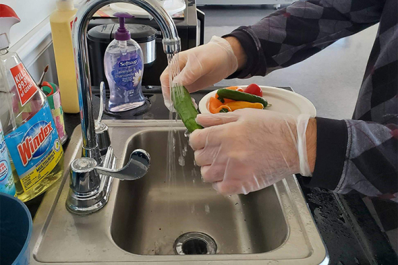 Closeup of person's hands washing vegetables in the sink