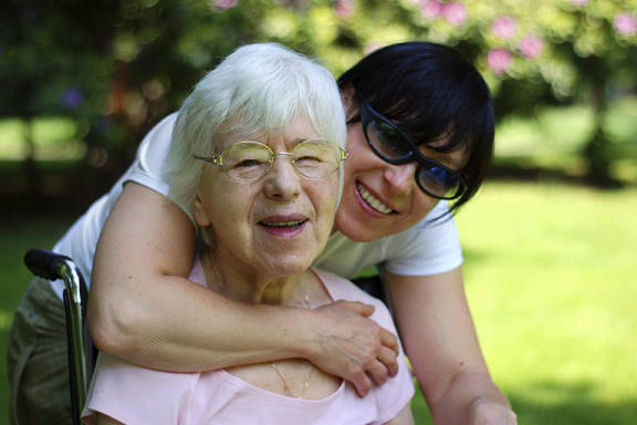 Smiling older adult woman being embraced by her adult daughter