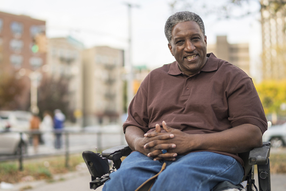 Smiling man sitting in wheelchair outside