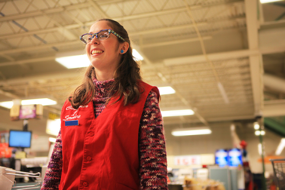 Smiling young woman in work uniform standing inside a store.
