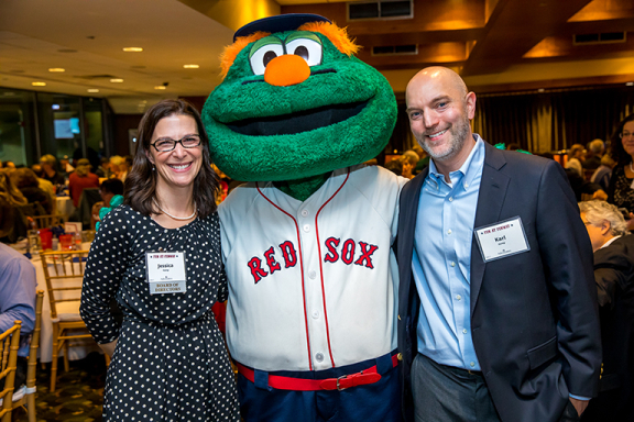 Jessica Kemp, Chair of Advocates Board of Directors, and husband Karl smiling with Wally the Green Monster at Advocates 6th Annual Gala.