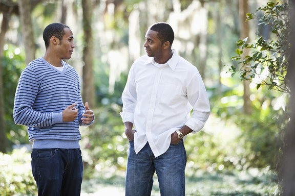 Young man having deep conversation with an older man outside.