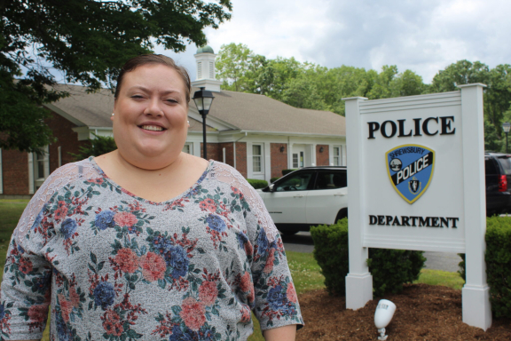Jessica Atwood smiling standing in front of the Shrewsbury police department sign outside.