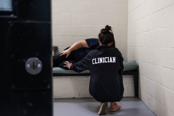 clinician talking to individual in jail cell