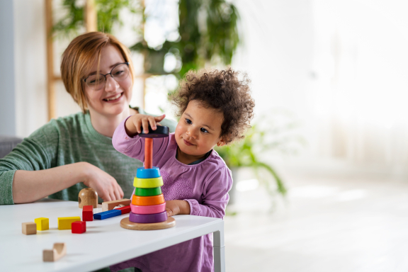 A smiling adult and toddler play with toys.