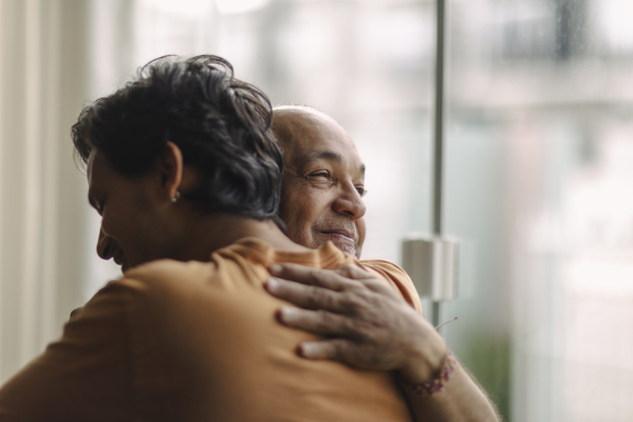 An older parent and adult child embrace