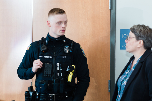 Police officer with redish blonde short hair in uniform speaks with a person with salt-and-pepper hair