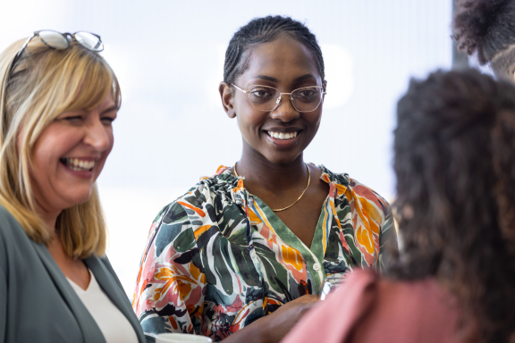 Three adults mingling and smiling