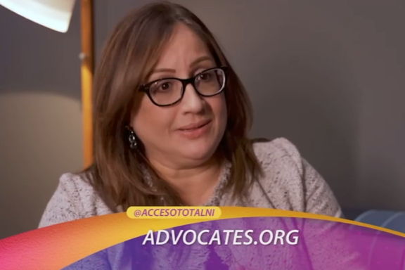 An adult with long straight brown hair and glasses is shown in a screenshot from a TV show