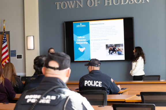 A group of officers sit in a conference room looking at a presentation on a screen.