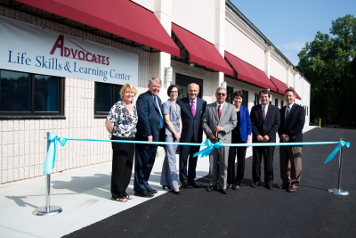 Advocates leadership in front of the Life Skills and Learning Center, preparing to cut the ribbon.