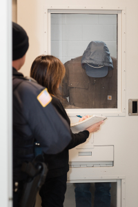 Clinician takes notes while speaking with a person behind a glass door